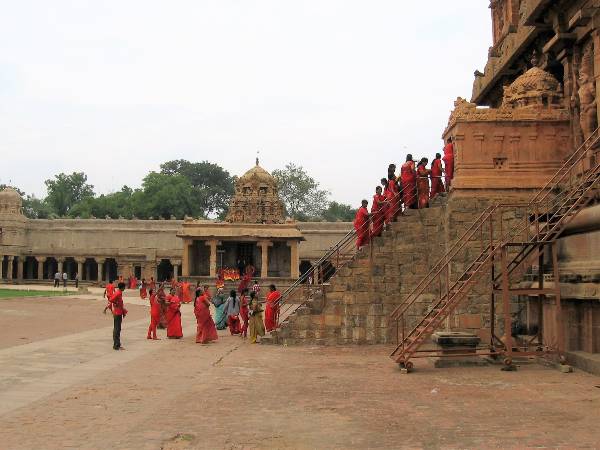 Pélerine habillés en rouge qui montent un escalier sur un temple