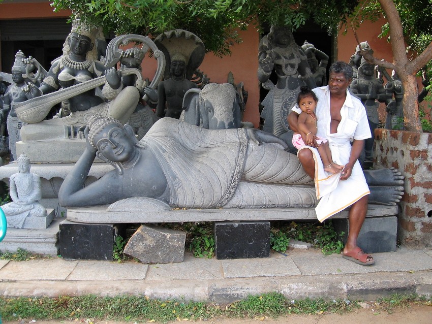 Mamallapuram Monsieur tenant un bébé, assis sur une sculpture de granit noir