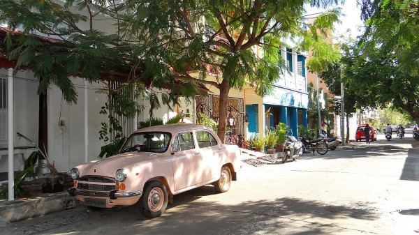 Veille voiture rose pâle dans une rue ombragée