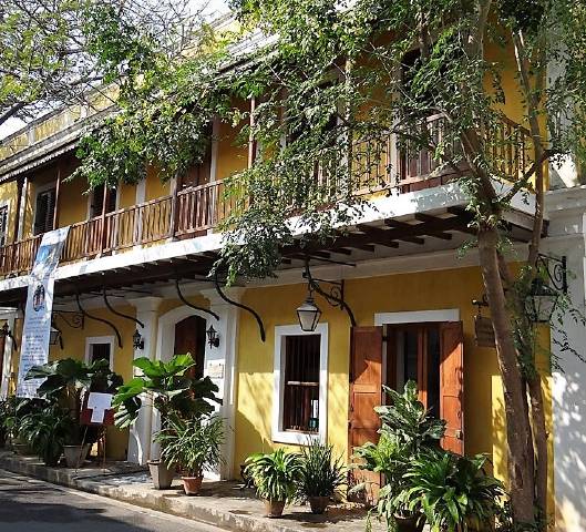 Maison coloniale jaune avec verdure