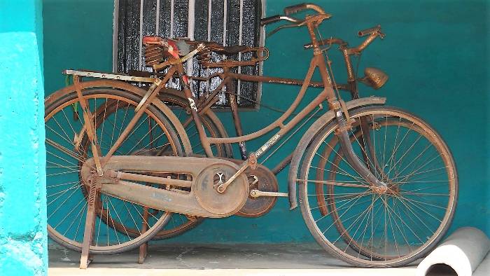 Vieux vélos rouillés devant une mur bleu