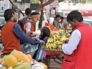 Inde barbier en action au milieu d'un stand de bananes, en pleine rue