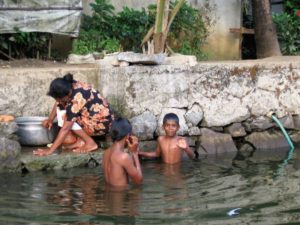 Des enfants qui jouent dans l'eau font signent à l'objectif