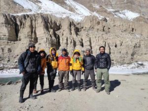 7 personnes en blousons chauds sont debout devant des montagnes
