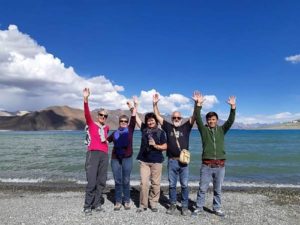 Ladakh 5 personnes lèvent les bras devant un lac