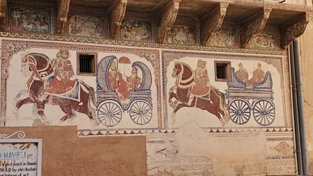 De vieilles peintures murales représentent des carrosses tirés par des chevaux