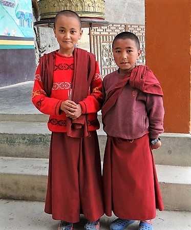 2 enfants moines en robe rouge qui posent devant l'objectif