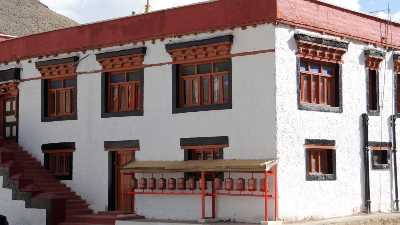 Maison blanche à toit rouge et moulins à prières