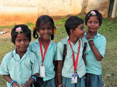4 fillettes en uniforme de leur école, sourient au photographe