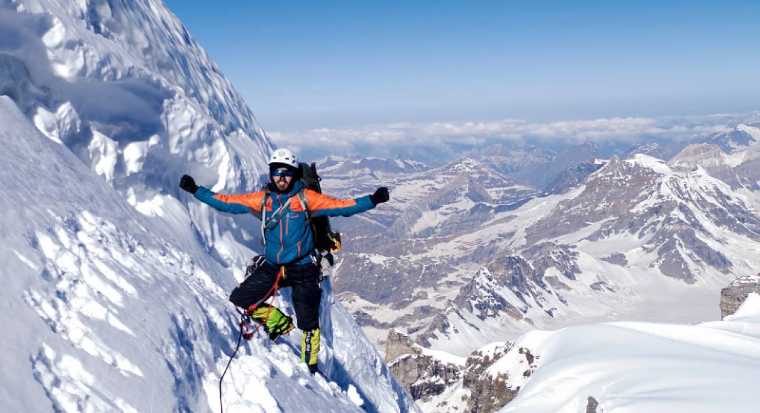 1 alpiniste sur une paroi faisant un signe de victoire