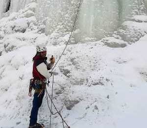 Un homme devant une paroi glacée assure un grimpeur