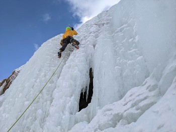 Un homme en jaune escalade une cascade de glace