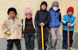 4 petits garçons adossés à un mur avec une batte de cricket