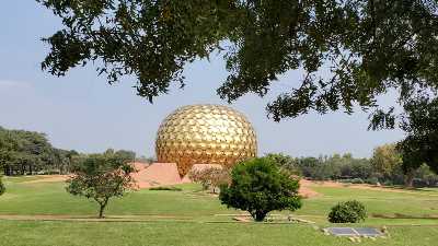 Immense sphère dorée, posée au milieu d'une jardin avec des arbres