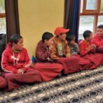 Des enfants moines assis par terre en tailleur qui écoutent