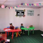 Salle de classe avec une table rouge et une verte et 2 écolières