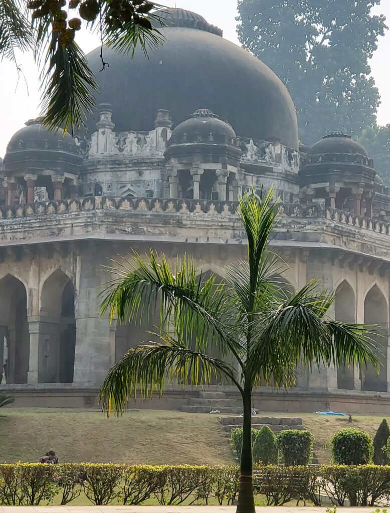 Vieux bâtiment avec un dôme derrière un palmier