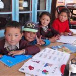 4 enfants alignés devant des livres de classe