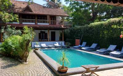 Piscine devant une maison avec balcon en bois