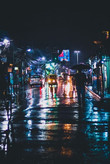 Une rue de nuit sous la pluie avec des phares de voitures