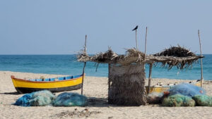 Une barque et des filets de pêcheurs sont sir une plage de sable devant la mer