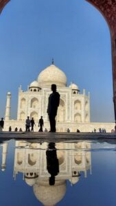 Une silhouette noire se détache devant le Taj Mahal, qui se felète dans l'eau