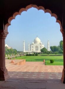 Au loin, derrière un porche, un jardin avec le Taj Mahal