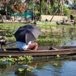 Homme en barque s'abritant du soleil sous un parapluie